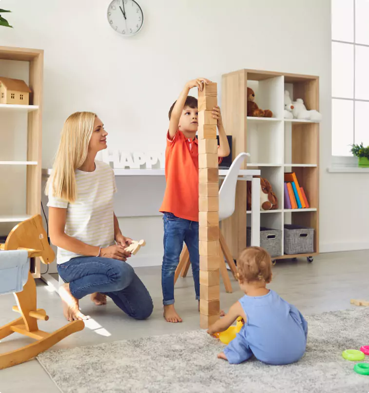 A woman and two children playing with wooden blocks in a living room, incorporating bumo.