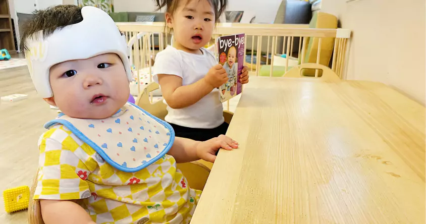 A baby is sitting at a table with a bib on.